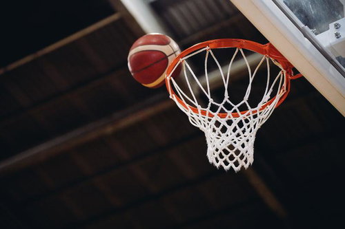 シュートしたバスケットボールがゴールのリングに向かう