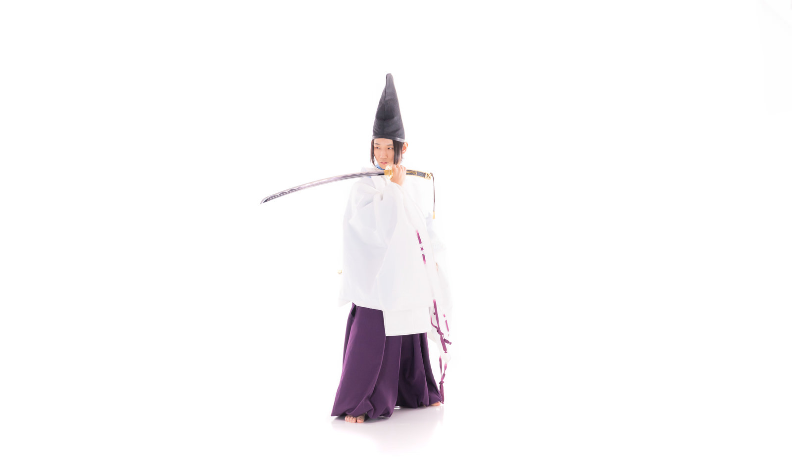 白い狩衣を着た剣士が刀を持って立っている様子［モデル：まーこ］