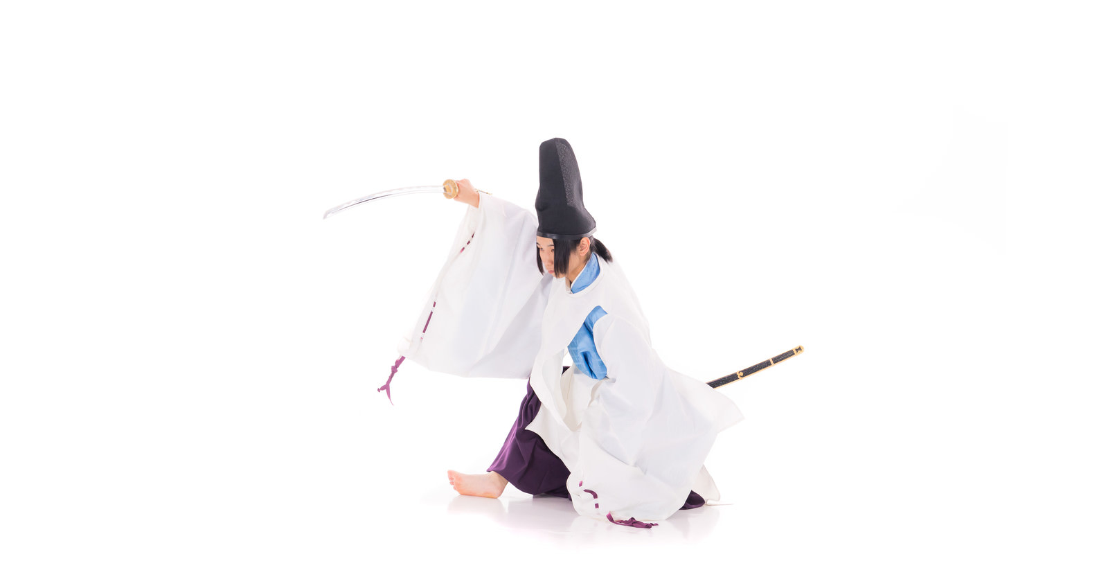 白い狩衣を着た侍がしゃがんだ状態から日本刀を振り上げるポーズ［モデル：まーこ］