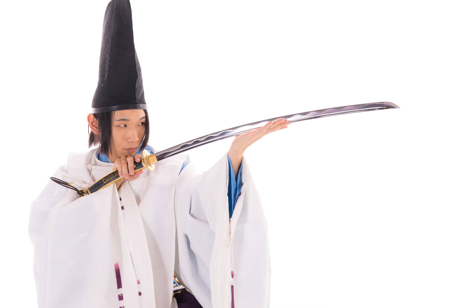 黒烏帽子と白狩衣の陰陽師が毛抜形太刀を抜刀姿勢で構えている男性［モデル：まーこ］