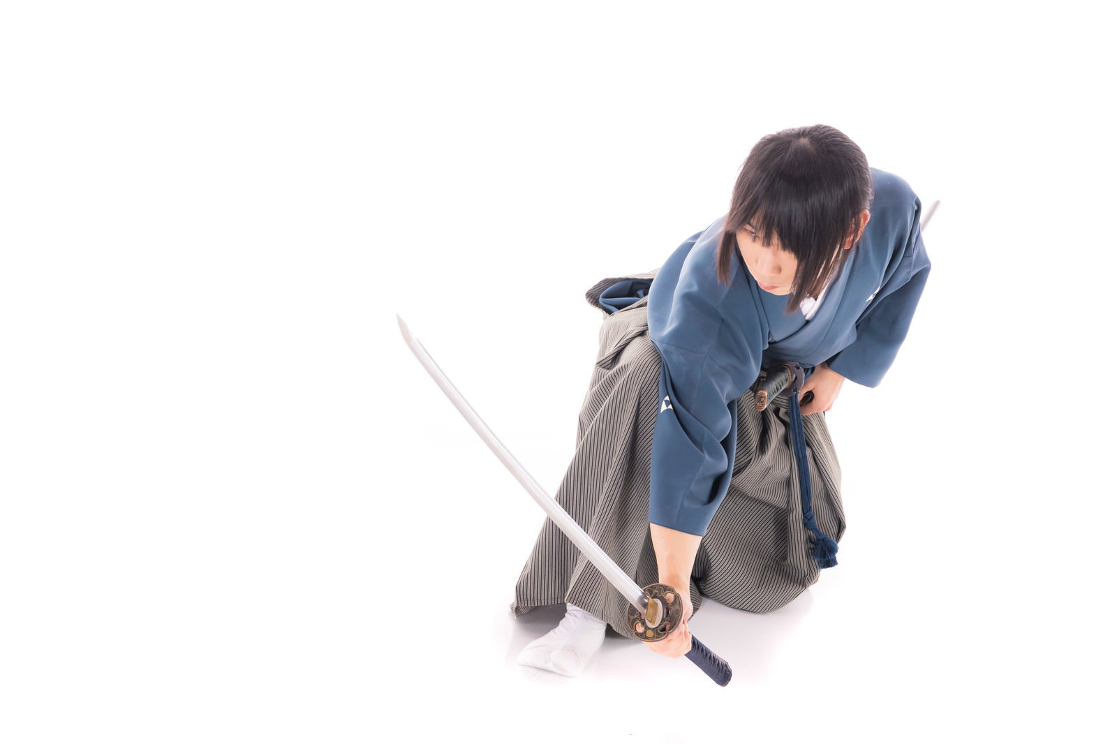 座った状態から日本刀を抜く動作をする男性［モデル：まーこ］
