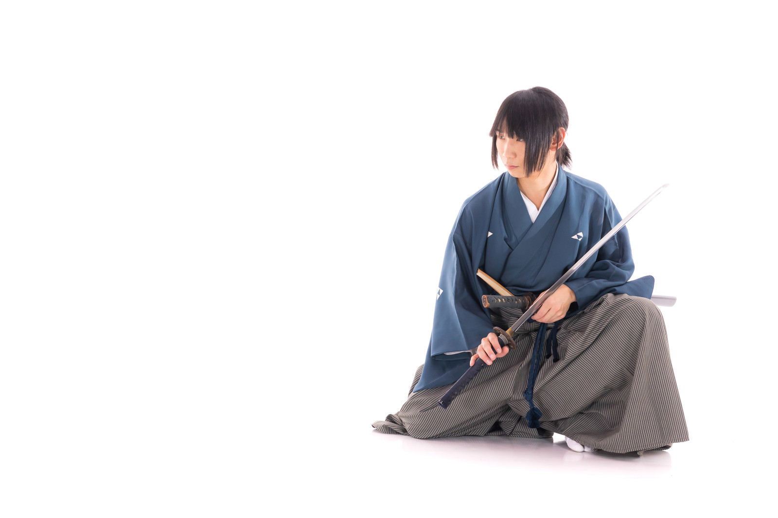 紺色の着物を着た侍が正座で刀を鞘に納める瞬間［モデル：まーこ］