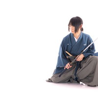 座った正座の姿勢で刀を納める侍の居合動作の写真
