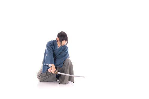 紺色の着物姿でしゃがみながら日本刀を構える侍
