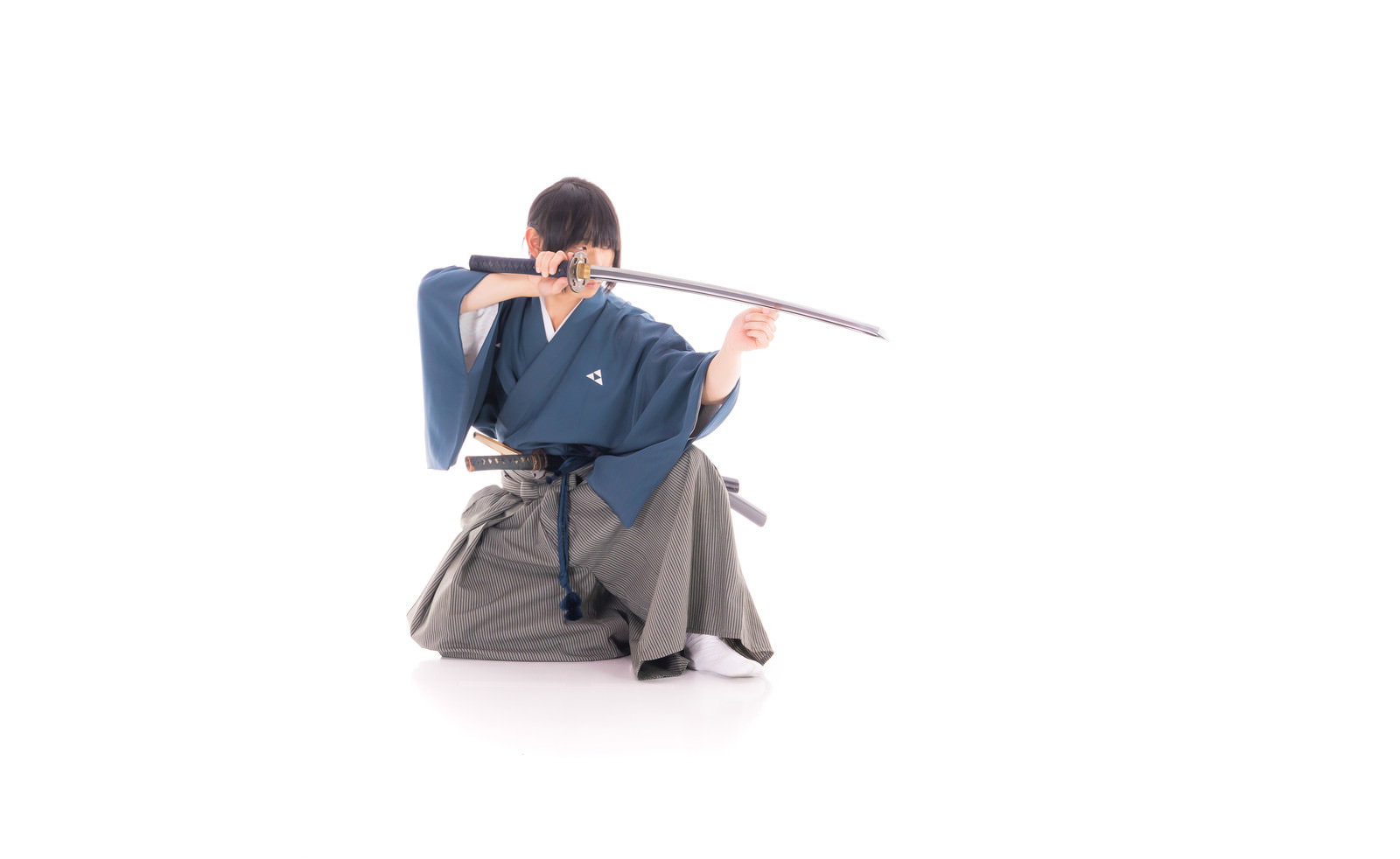 紺色の袴と紋付を着た侍が日本刀を構えて敵を見据えている様子［モデル：まーこ］