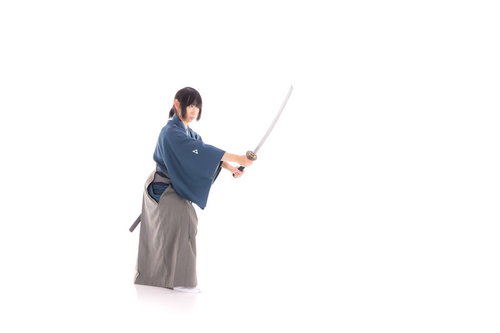 ポニーテール姿で日本刀を抜刀する侍の凛々しい姿勢