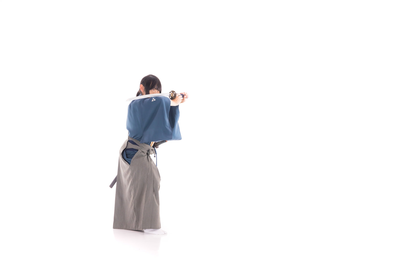 袴を着た男性が日本刀を両手で構える剣士のポーズ［モデル：まーこ］