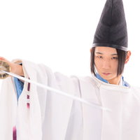 白い狩衣を身に纏い刀を抜く剣士の瞬間を捉えた時代劇写真の写真