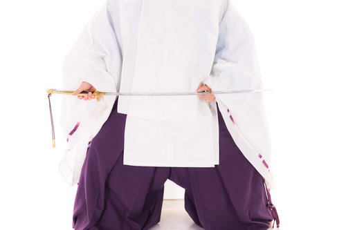 白い狩衣姿で毛抜形太刀を納刀する男性の動作