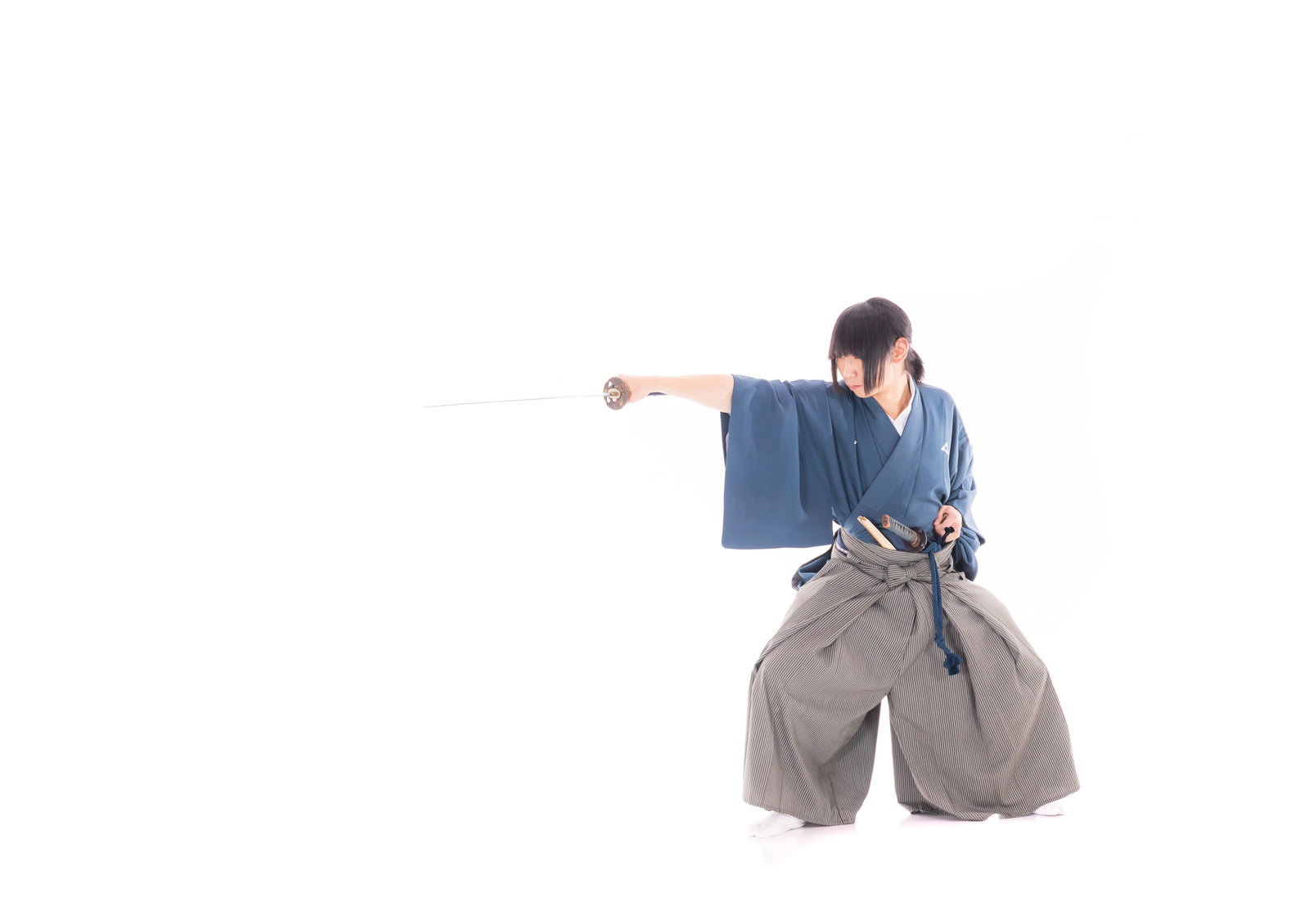 紺色の着物と灰色の袴を着た侍が刀を構えて居合の型を決めている［モデル：まーこ］