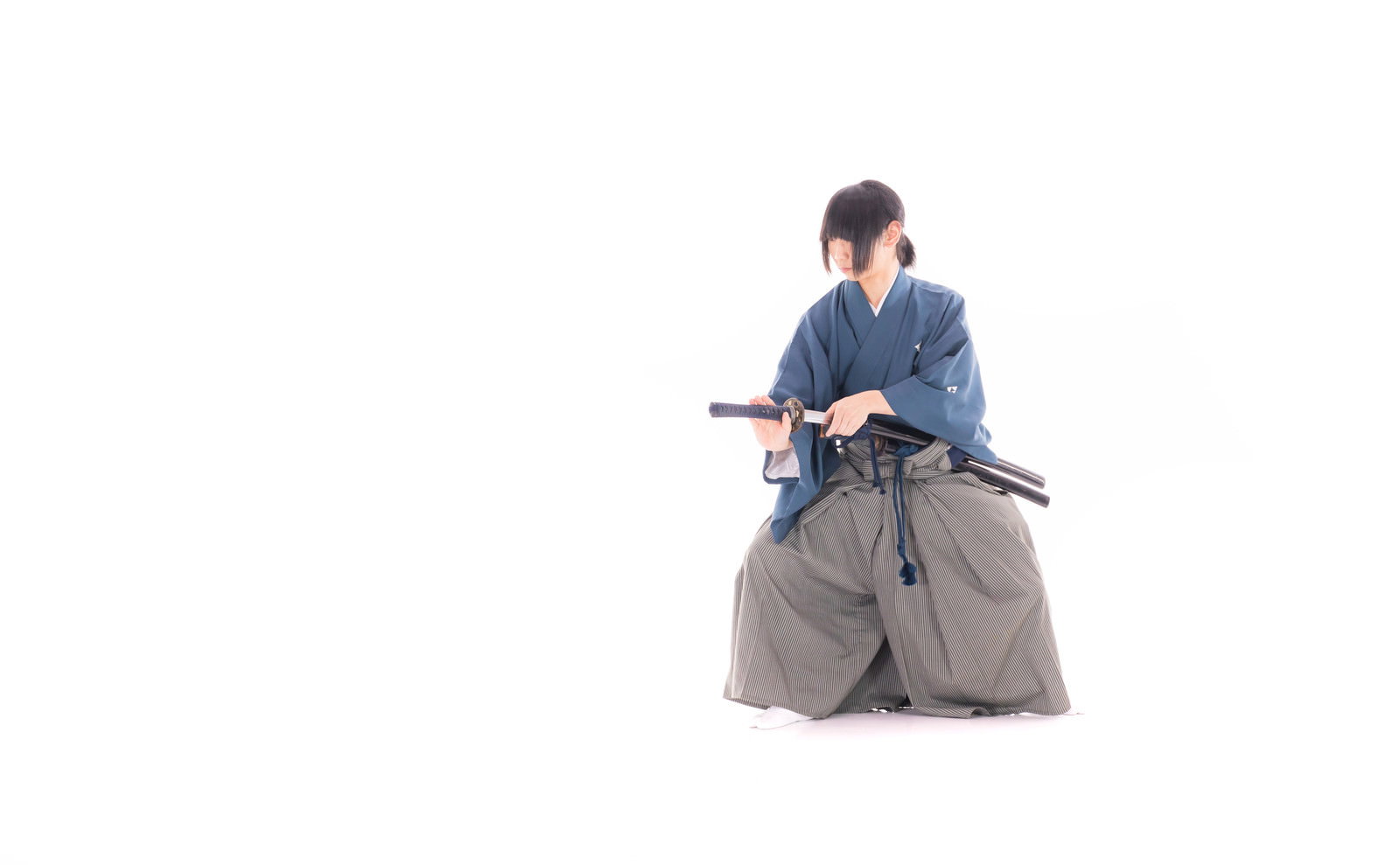 白い背景で正座をして刀を鞘に納める和装の刀剣男士［モデル：まーこ］