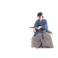 刀を鞘に納める侍の納刀。正座姿勢で丁寧に太刀を扱う剣士の写真
