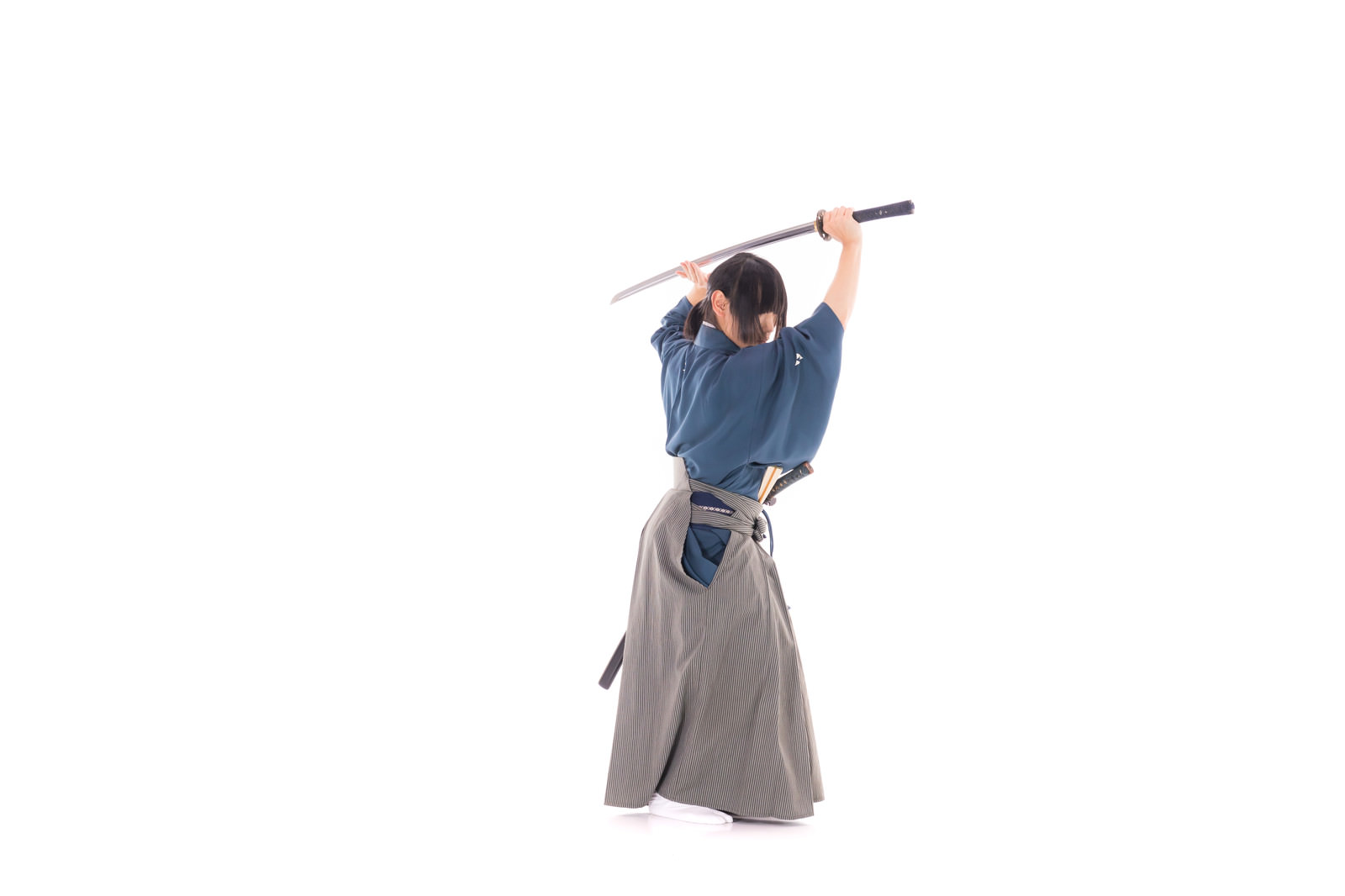 紺色の着物と袴姿で太刀を振り上げる侍の男性［モデル：まーこ］