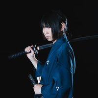 黒背景のスタジオで刀を担ぐ女侍の写真