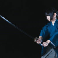 暗闇の中、紺色の着物で刀を抜く若い侍の決闘シーンの写真