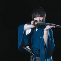 暗がりの中、鋭い眼差しで剣先を見つめる侍の写真