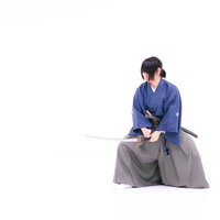 紫の着物を着た侍による血振るい（チブルイ）の所作の写真