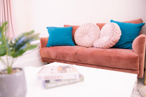 ピンク色の2人掛けソファーとクッションが置かれたリビング
