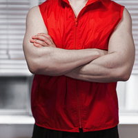 赤いベストを着てドヤ顔で腕組みする自信満ちた男性の写真