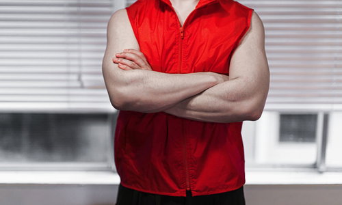 赤いベストを着てドヤ顔で腕組みする自信満ちた男性