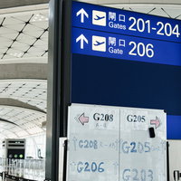 空港の搭乗口指導標とPCRエリアを指す手書きの案内紙の写真