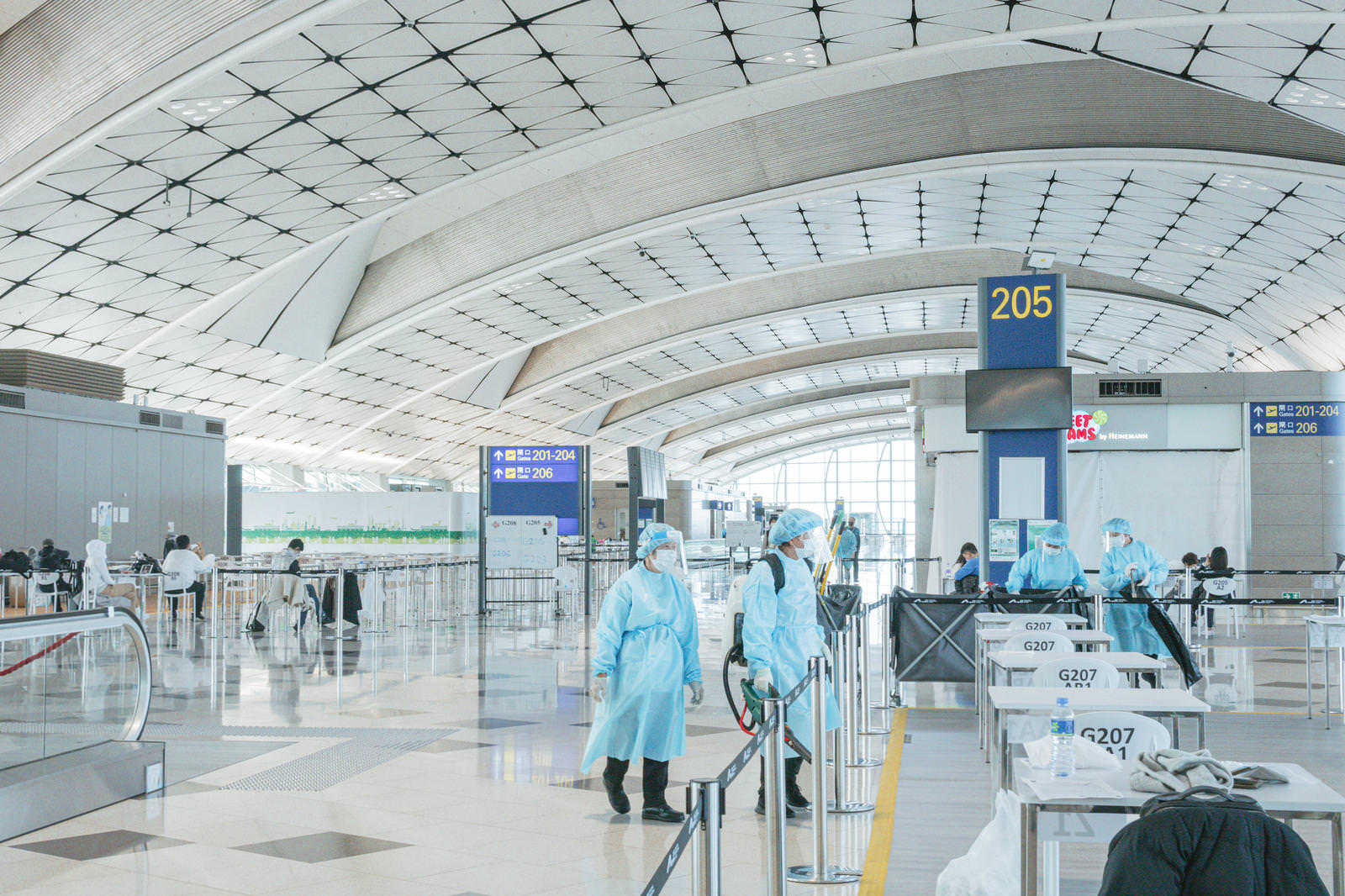 防護服を着用した医療従事者が空港検疫所で検査業務を行っている様子