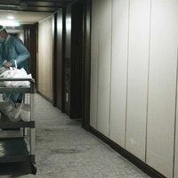 薄暗い廊下で防護服を着用して検査業務を行う医療従事者の写真