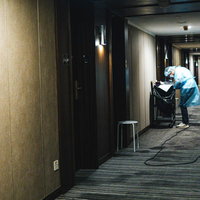 隔離棟の廊下で防護服を着用して従事する医療従事者の写真