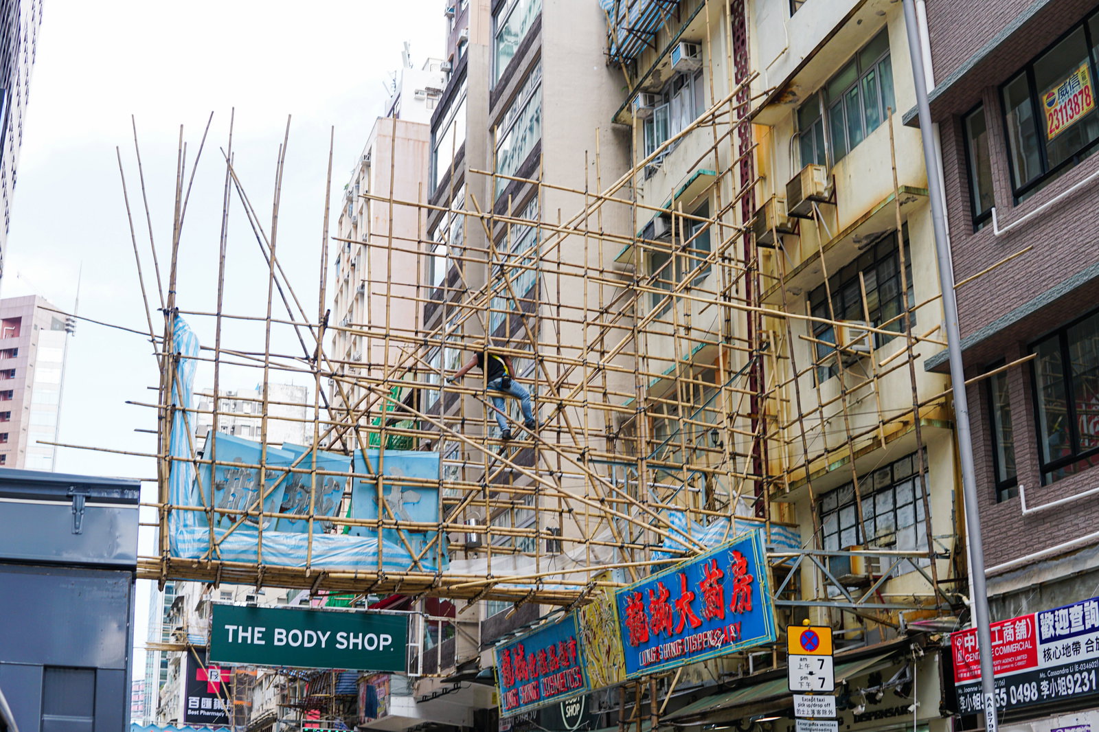 香港の高層建物に組まれた竹製の足場と看板が見える街並み