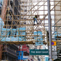 香港の道路を跨ぐ竹足場と青い工事看板の建築現場風景の写真