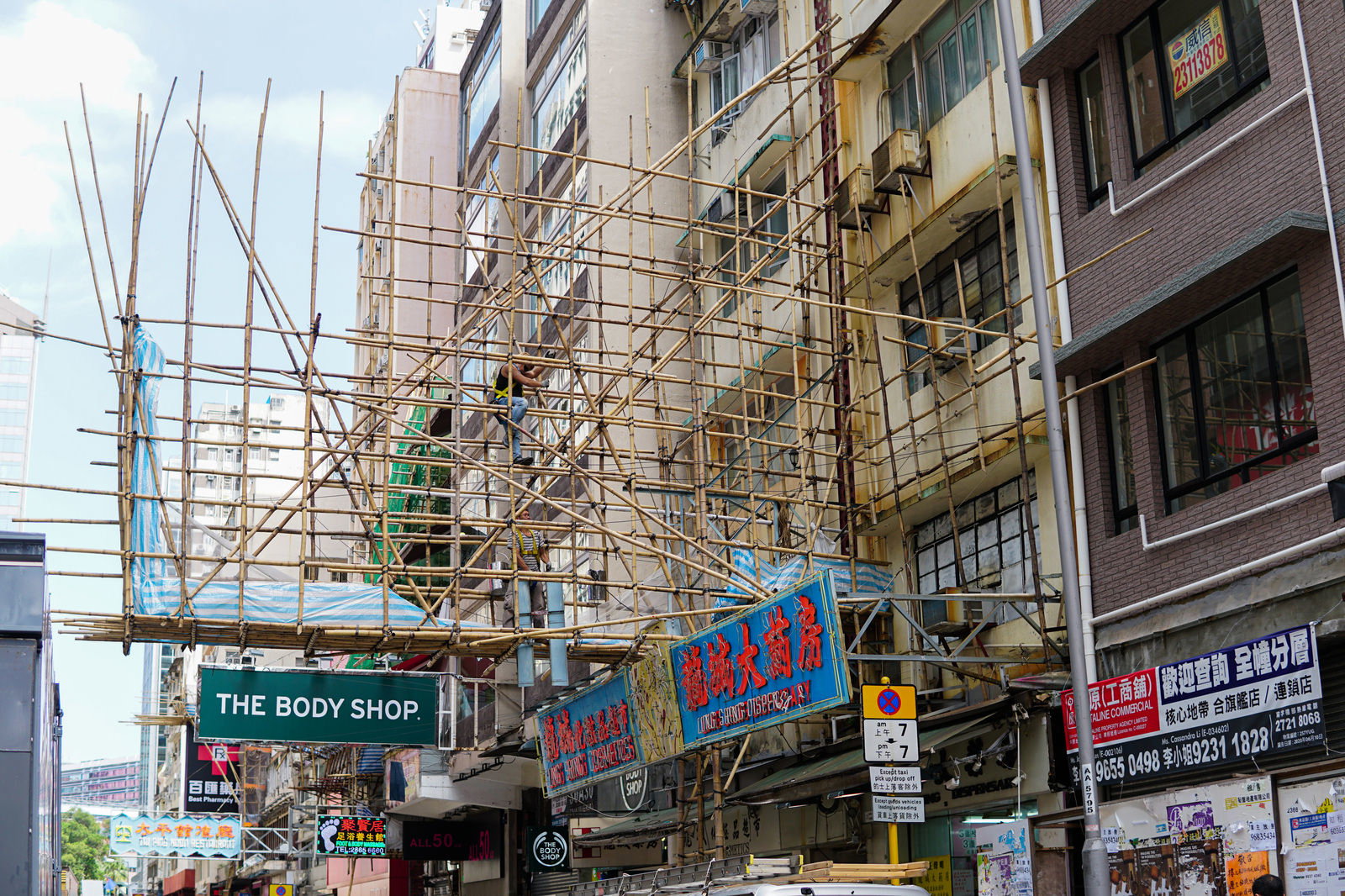 香港の街中で建物の外壁に組まれた竹製の足場と周辺の看板