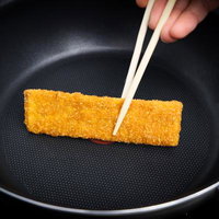 フライパンで焼くカツを箸で返すおやつの調理風景の写真
