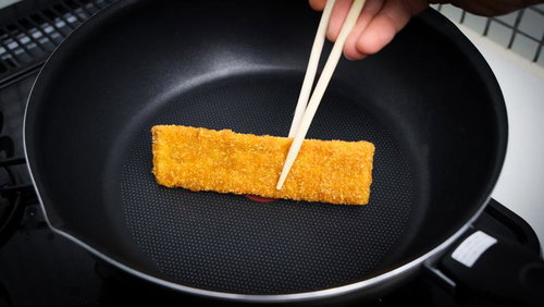 フライパンで焼くカツを箸で返すおやつの調理風景