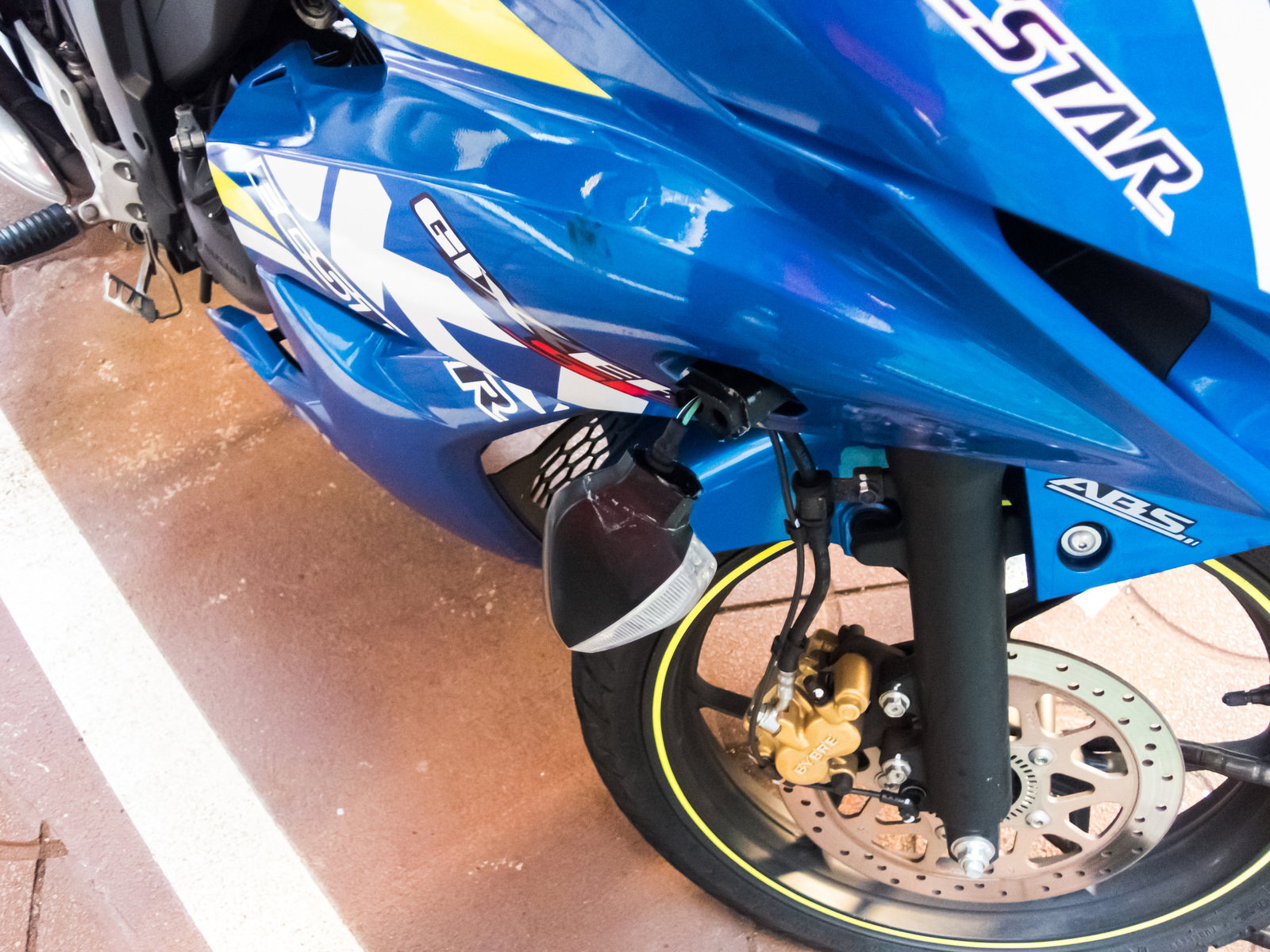 事故で破損し垂れ下がったバイクの青色ウインカーランプ