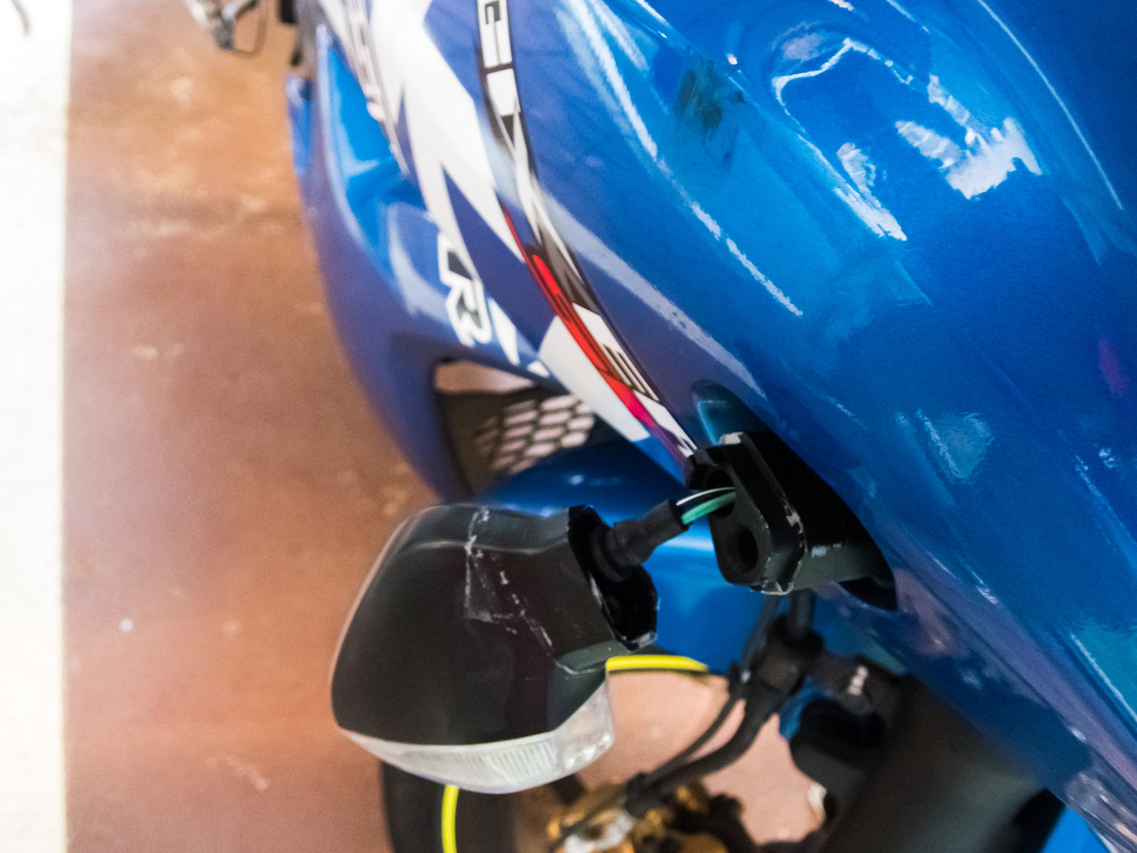 青いバイクの右側面で折れて破損したウインカーランプ