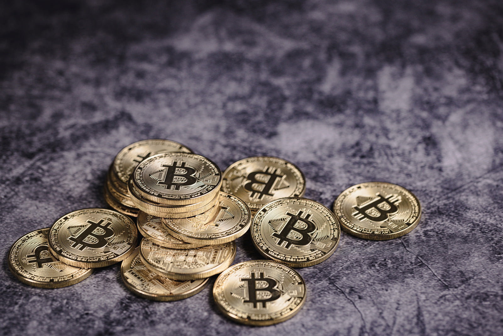 石材の床に散らばる金色のビットコインコイン複数枚