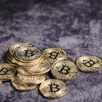 石材の床に散らばる金色のビットコインの写真