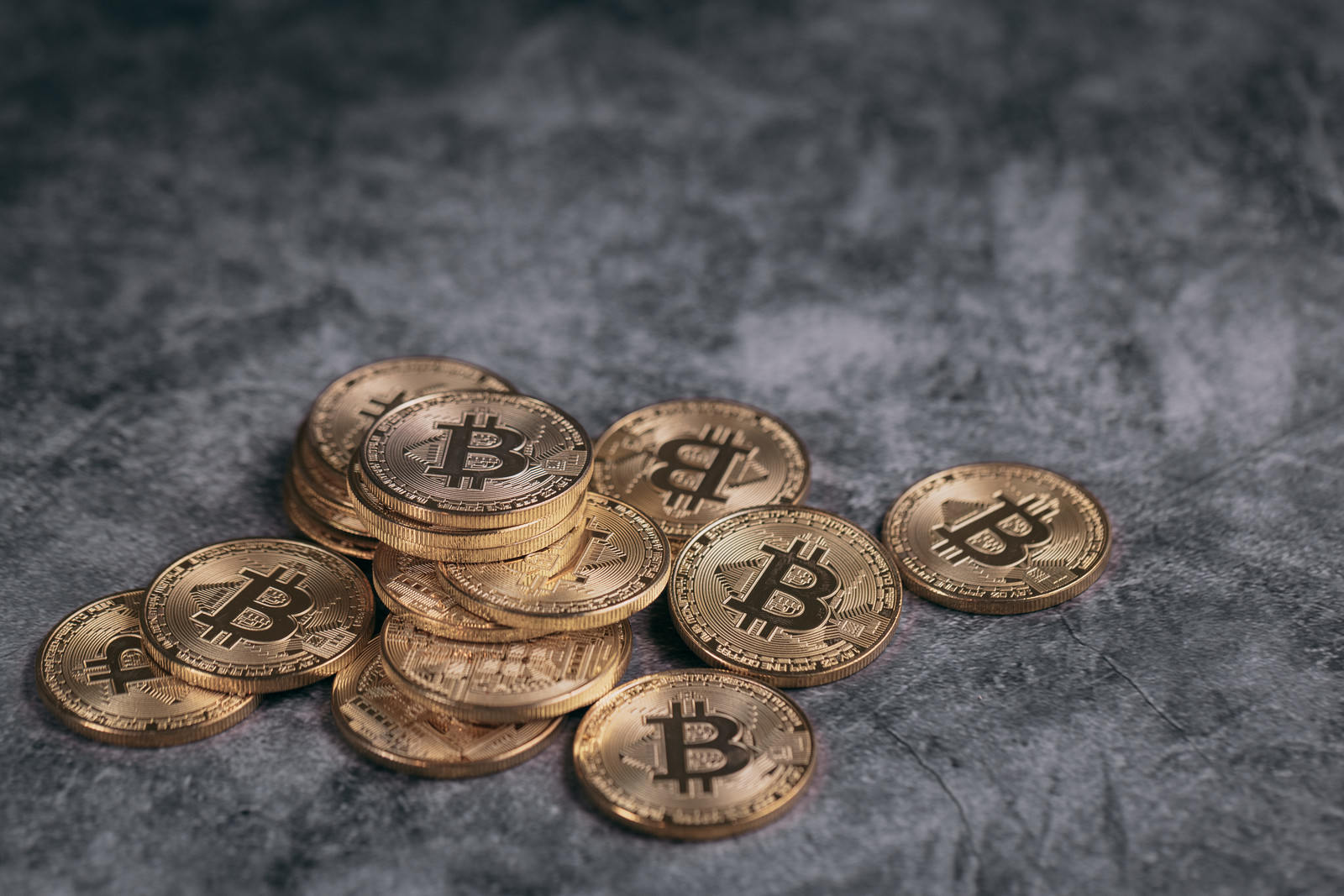 グレーの背景に散らばった金色のビットコインコイン