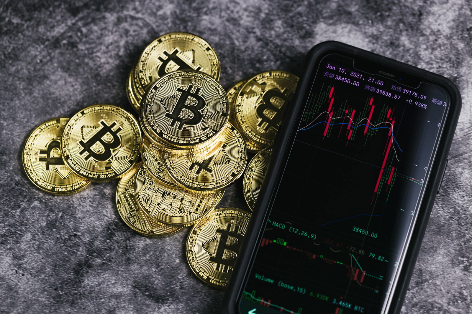 スマートフォンの暴落チャート画面と金色のビットコインコイン
