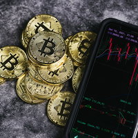 スマートフォンのチャート画面とビットコインの写真