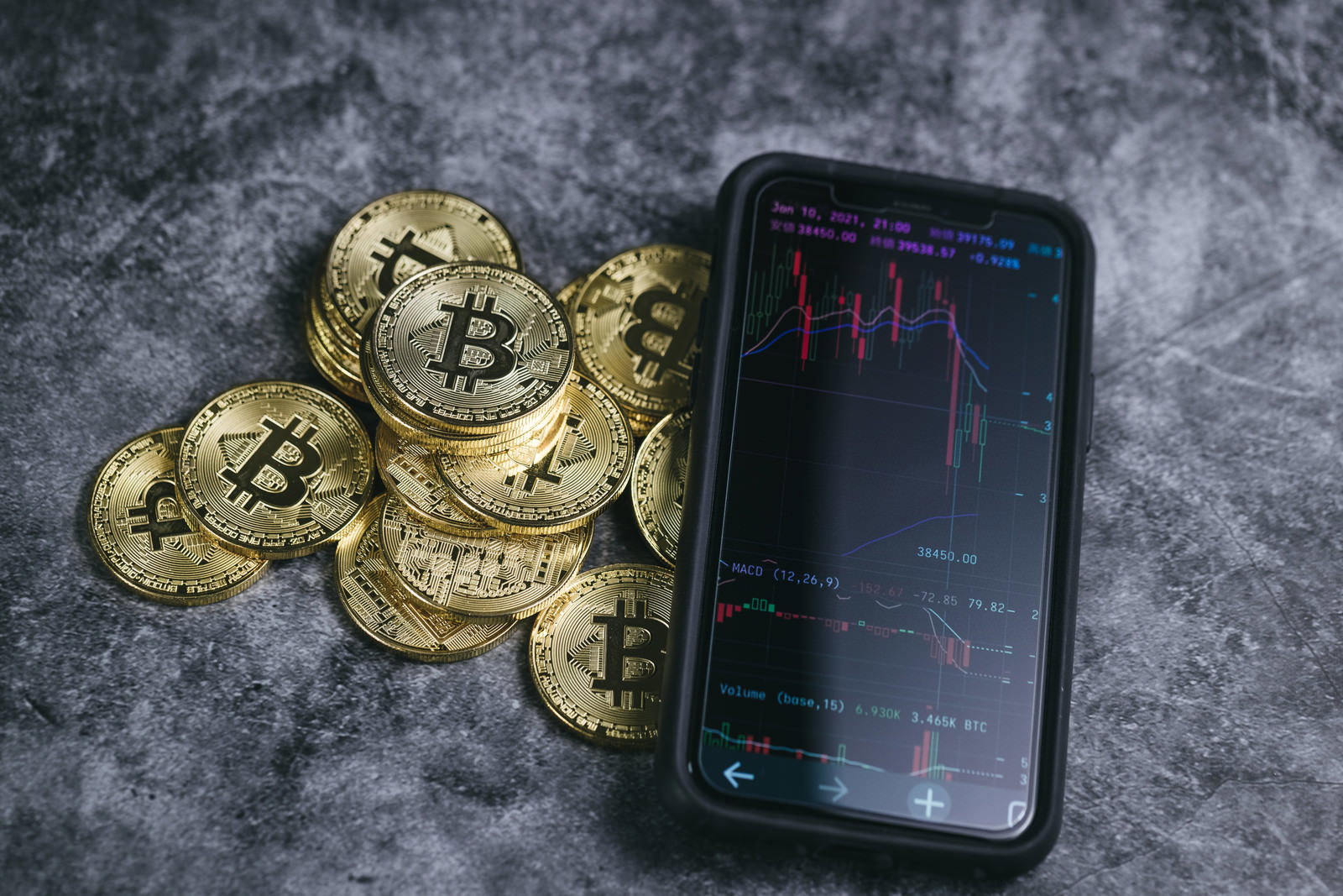 下降チャートが表示されたスマートフォンと金色のビットコイン