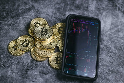 スマホのチャート画面とビットコイン、下降トレンド