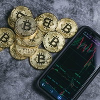 積まれたビットコインと横に置かれたスマートフォンの写真