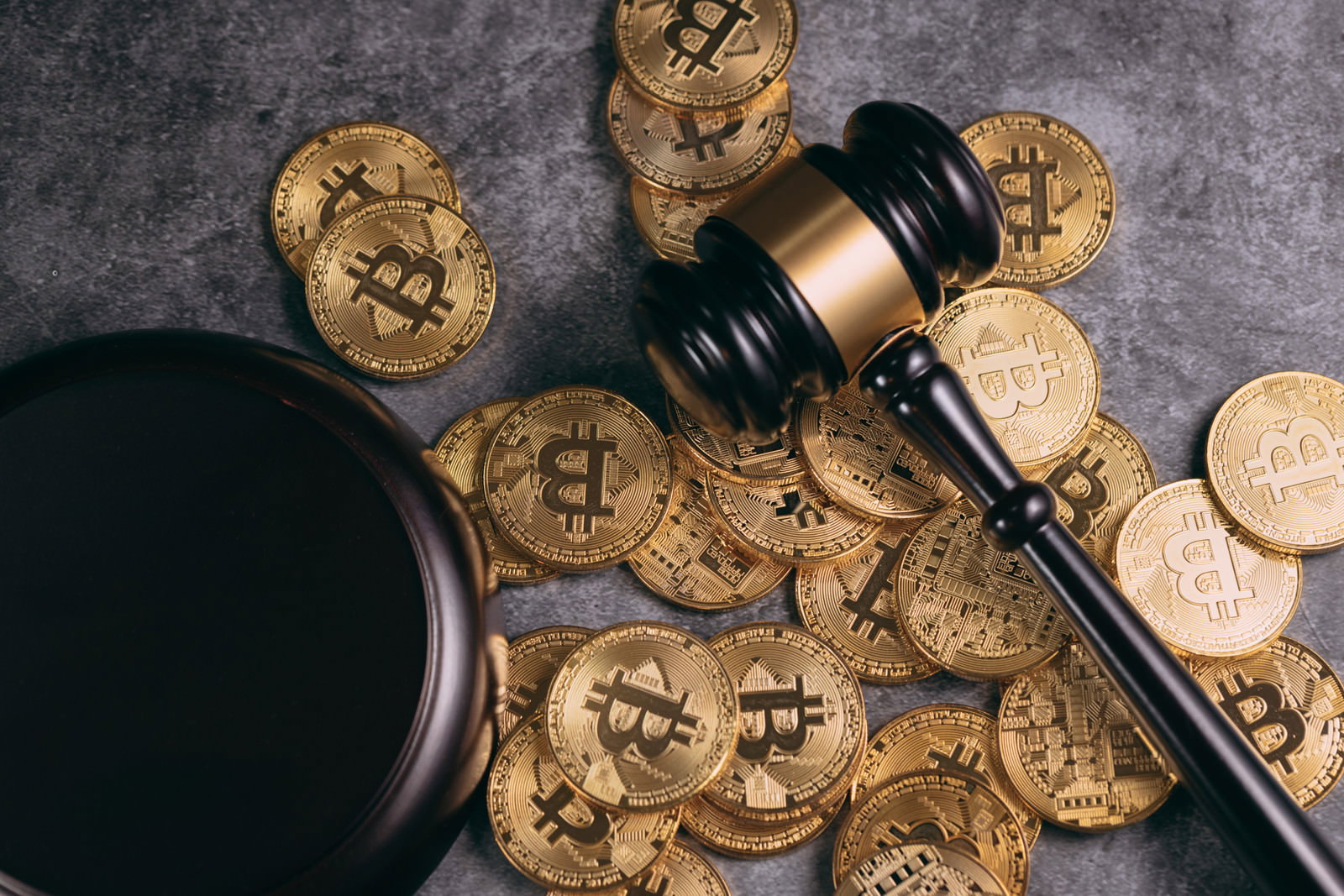 暗い背景に散らばった金色のビットコインコインと木製のガベル（小槌）