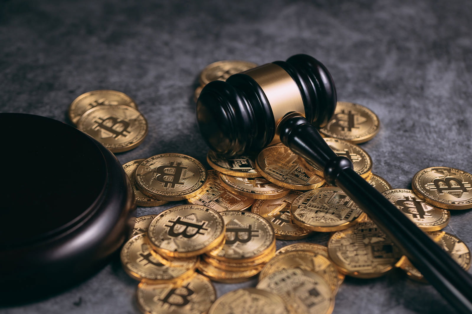 黒い背景に散らばる金色のビットコインと木製のガベル