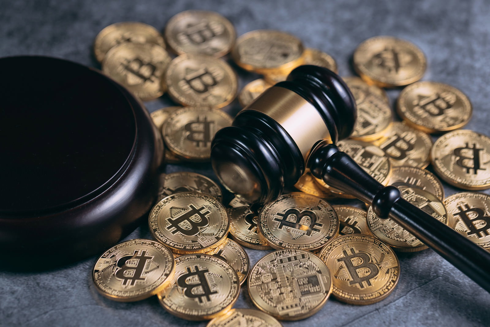 金色のビットコインコインが散らばる中に木製のガベル（小槌）が横たわっている様子