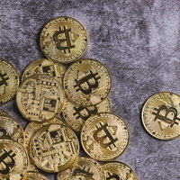 グレーの背景に裏表に散らばる金色のビットコインの写真