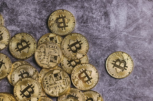 グレーの背景に裏表に散らばる金色のビットコイン