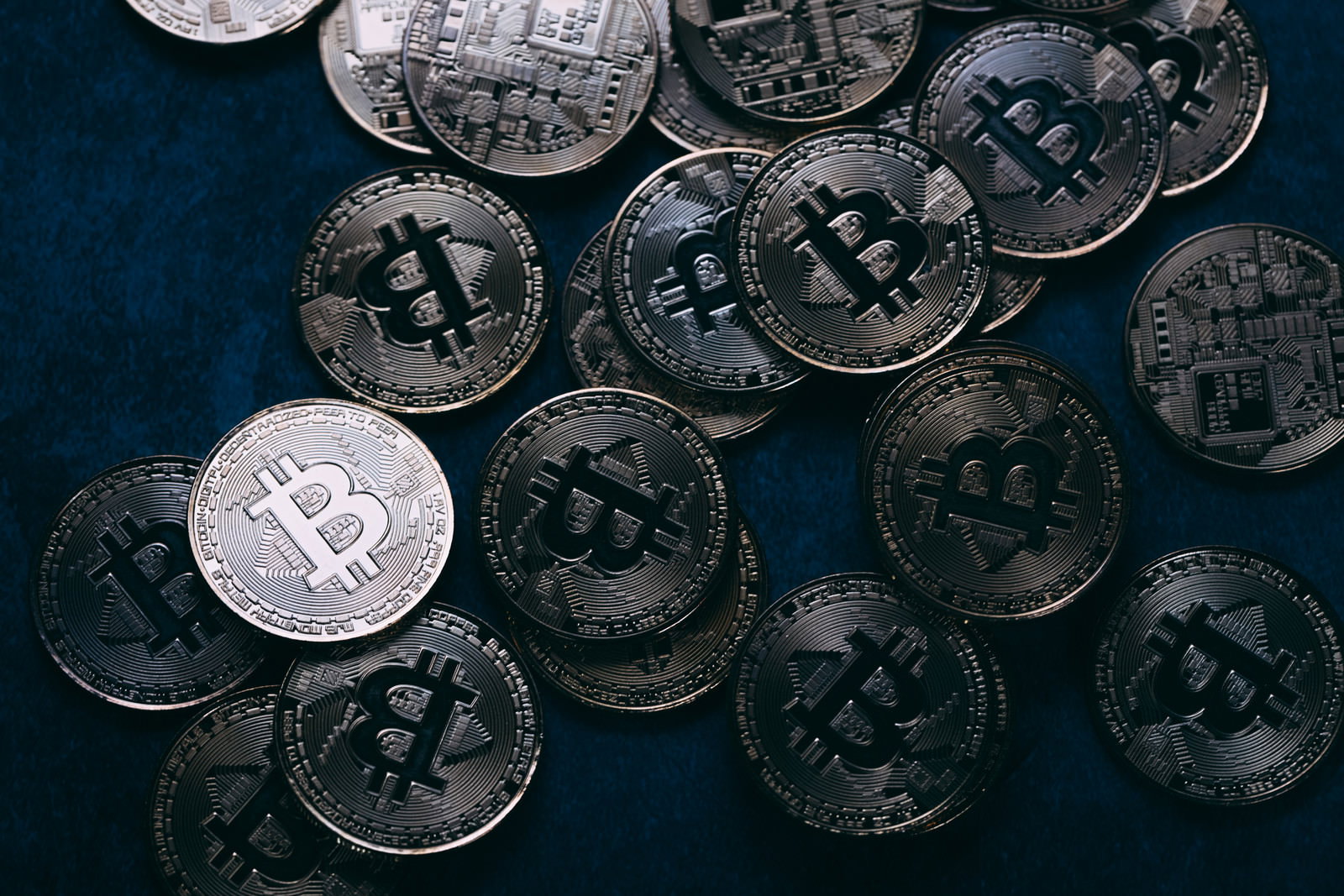 濃紺の布の上に散らばるビットコイン銀貨
