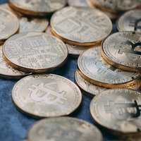 青い背景に散らばる金色のビットコインメダルの写真